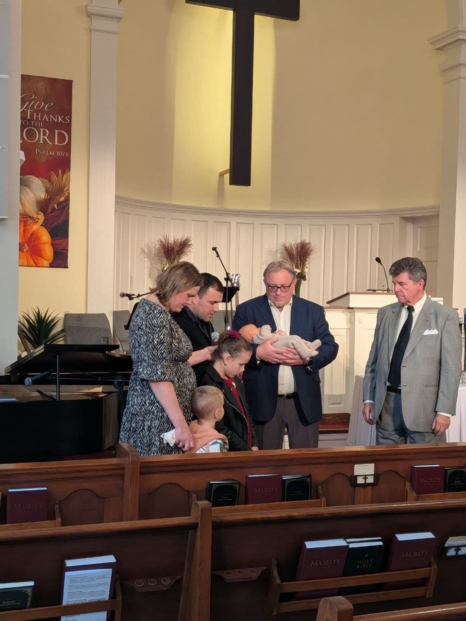 Denys and Anya's family with baby Mark receiving a prayer of blessing at church