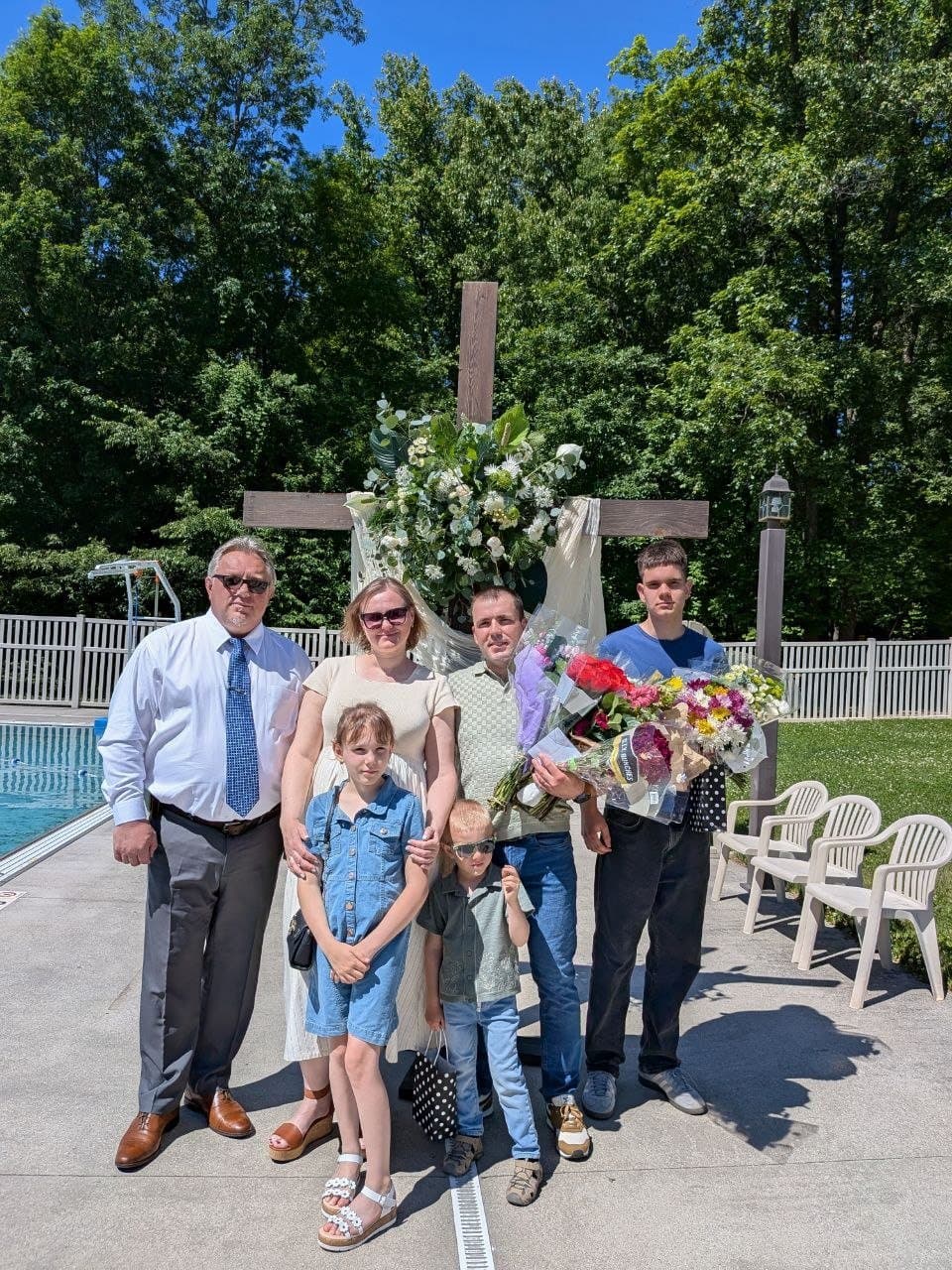 The newly baptized believer's family with flowers by the cross