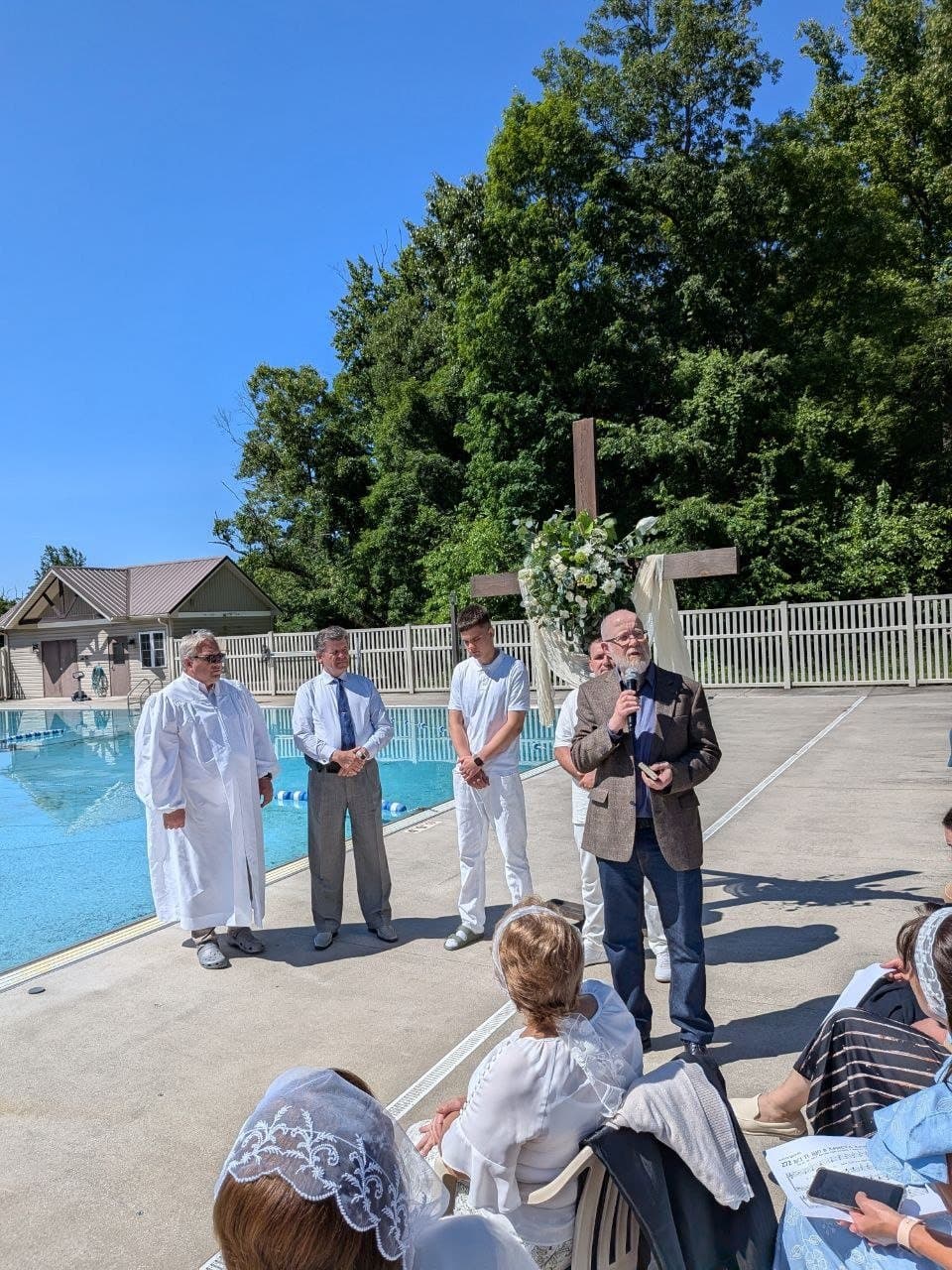 Pastors, baptism candidates, and the congregation gathered by the cross